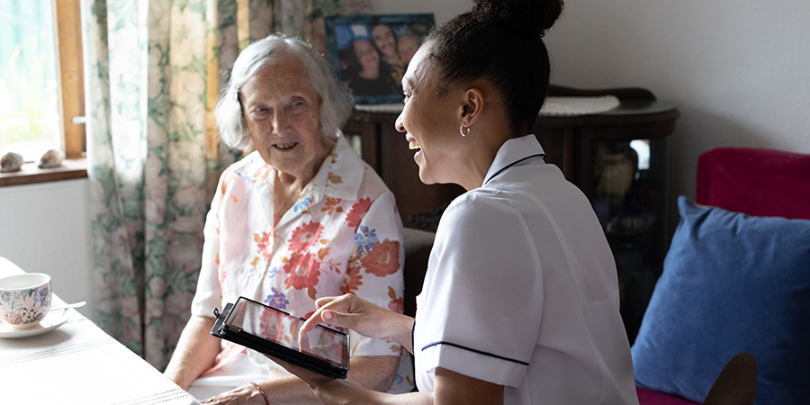 Nurse using digital table when meeting with elderly female patient